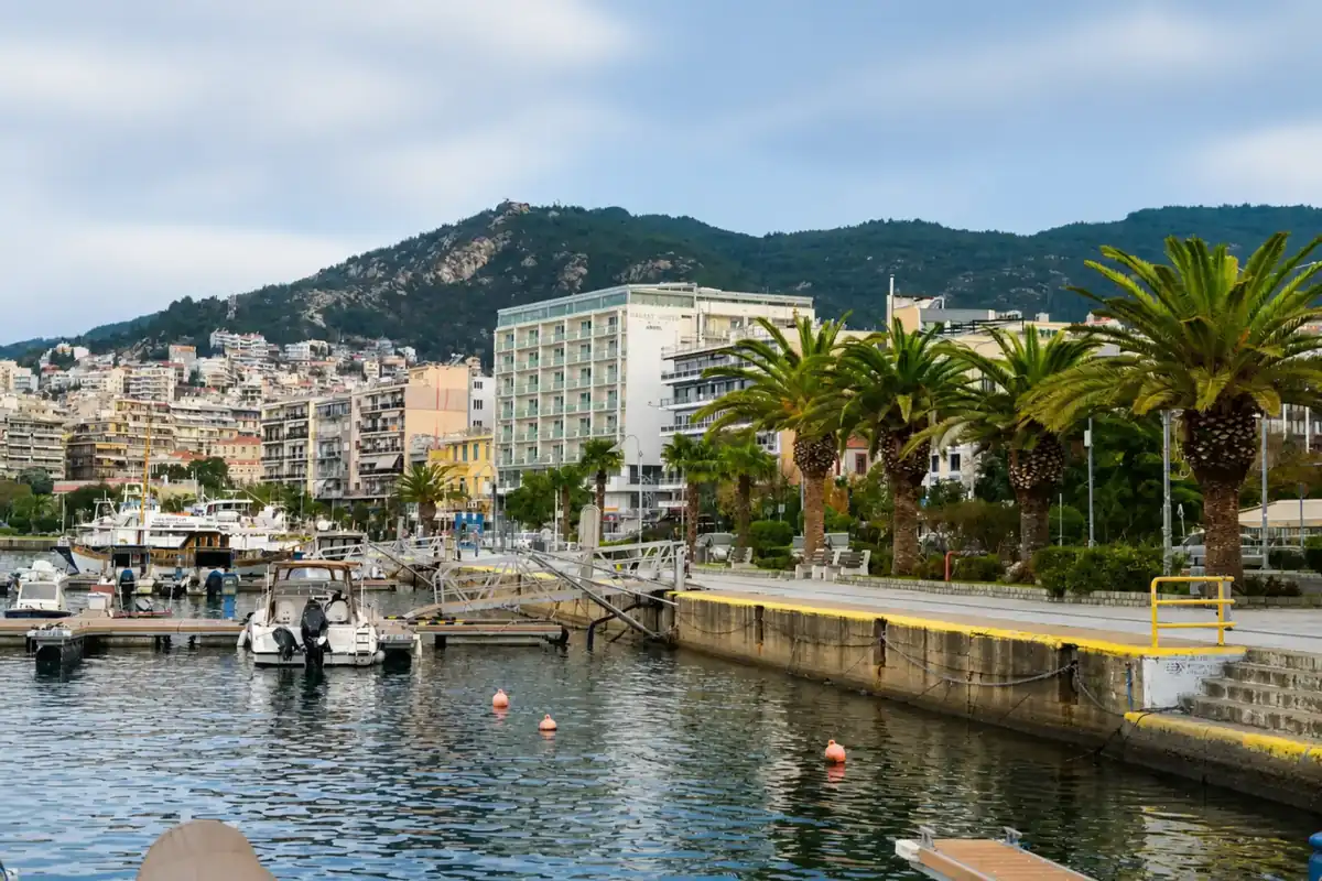 Kavala harbour with moored boats and the palm-lined waterfront promenade